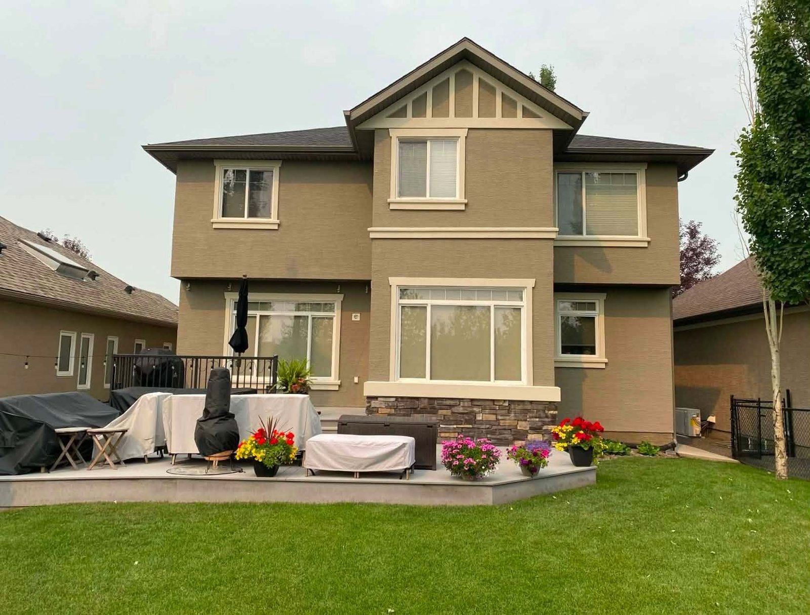 Back of a two-storey Calgary home with a fresh exterior repaint, seen from the garden patio