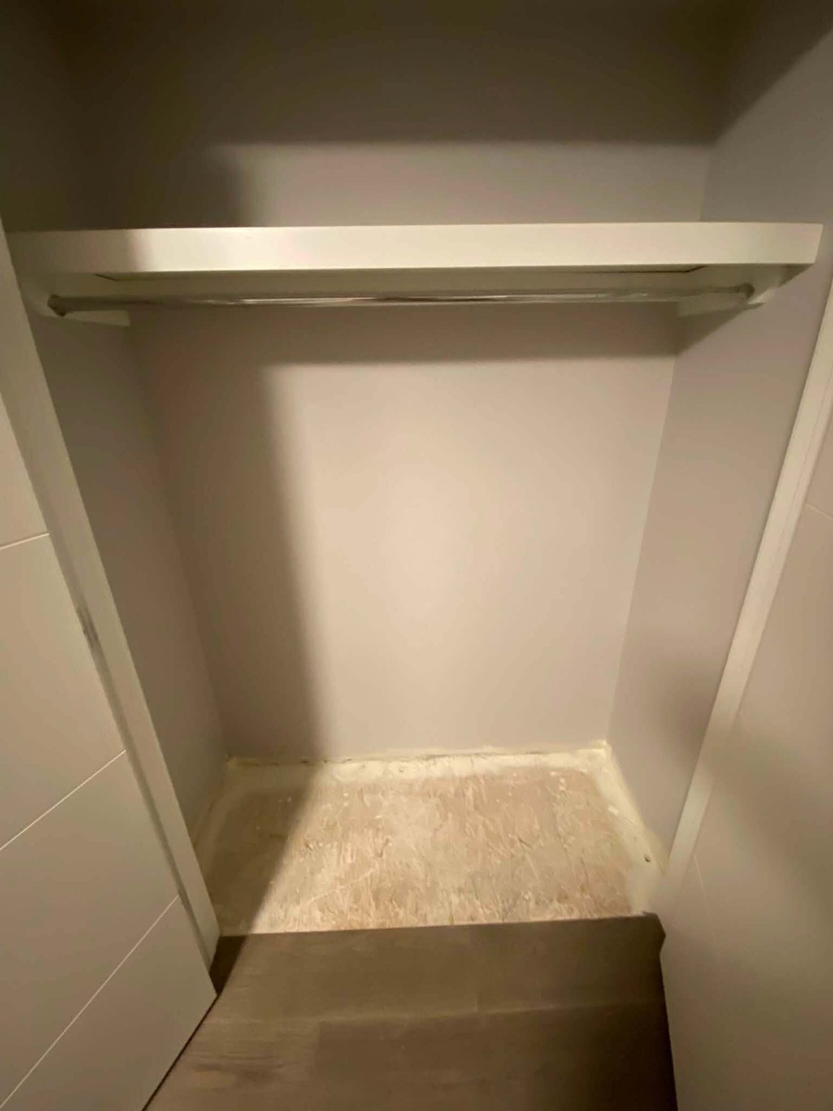 Finished closet after drywall repair and paint, with the shelf and rail back in place