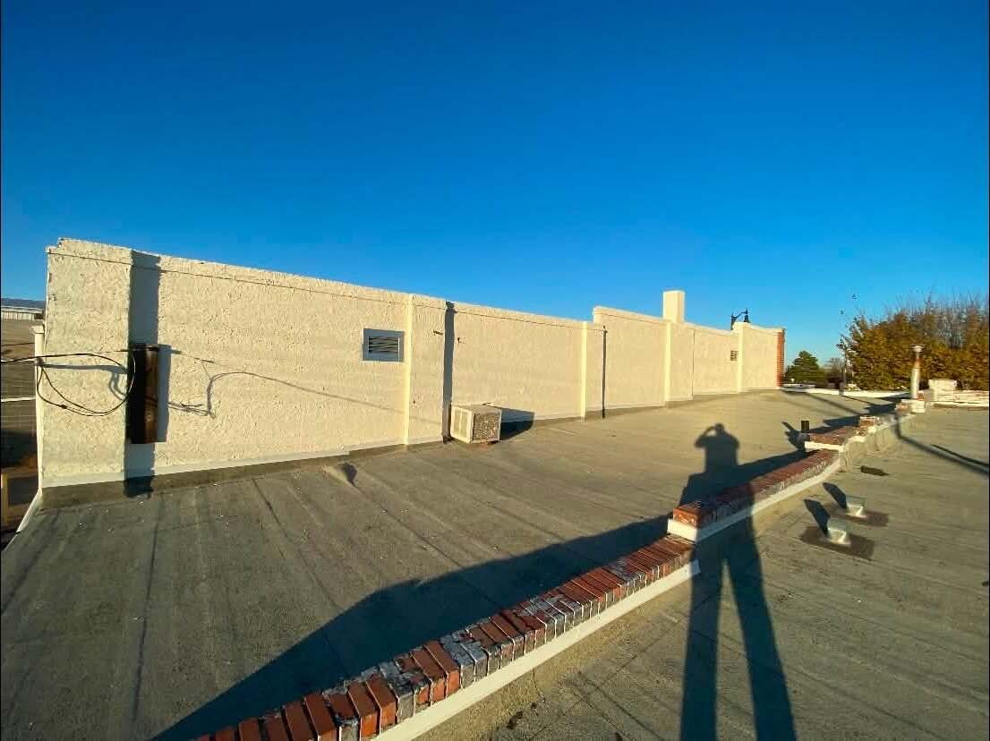 Clean cream stucco parapet of a commercial building after repainting, viewed along the roofline
