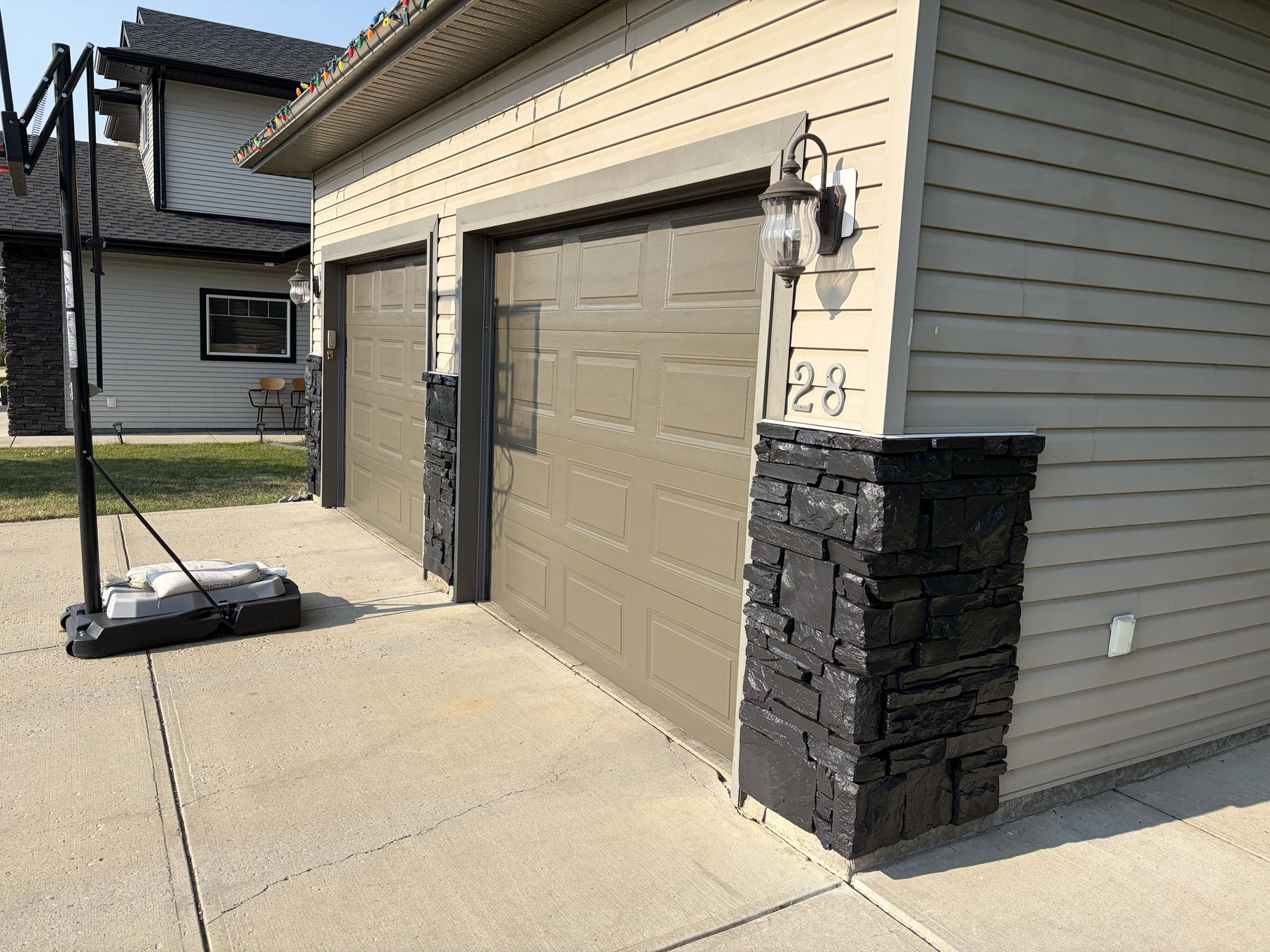 Garage doors and stone-clad exterior of a Red Deer home, finished in a warm taupe