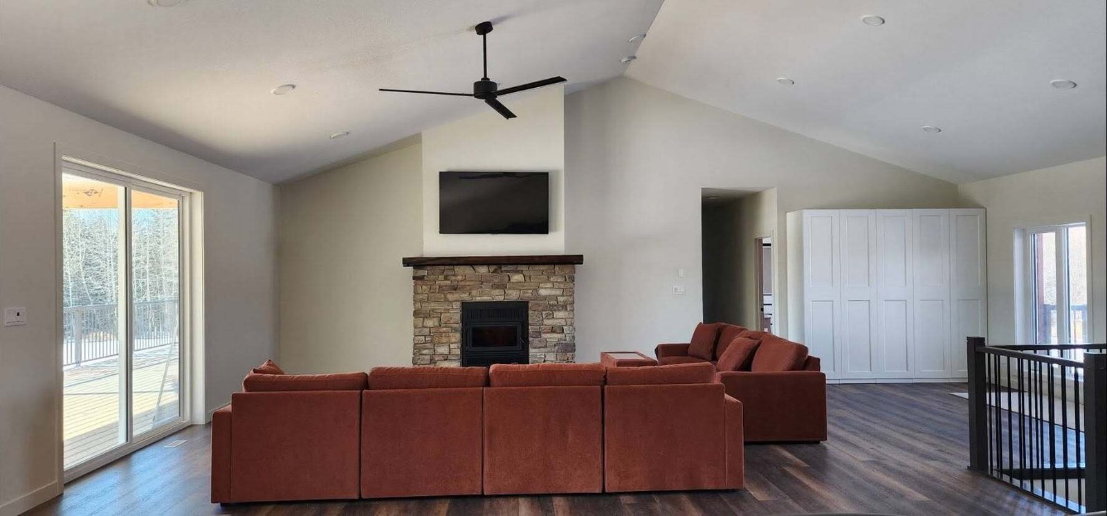 Great room with a stone fireplace in a new Lacombe County home, walls freshly painted
